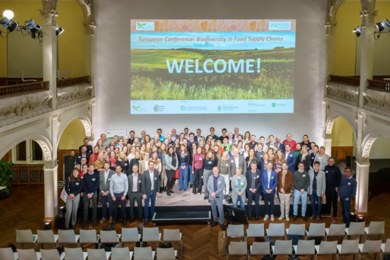 european panel event - everyone stood on stage with "Welcome" banner behind them